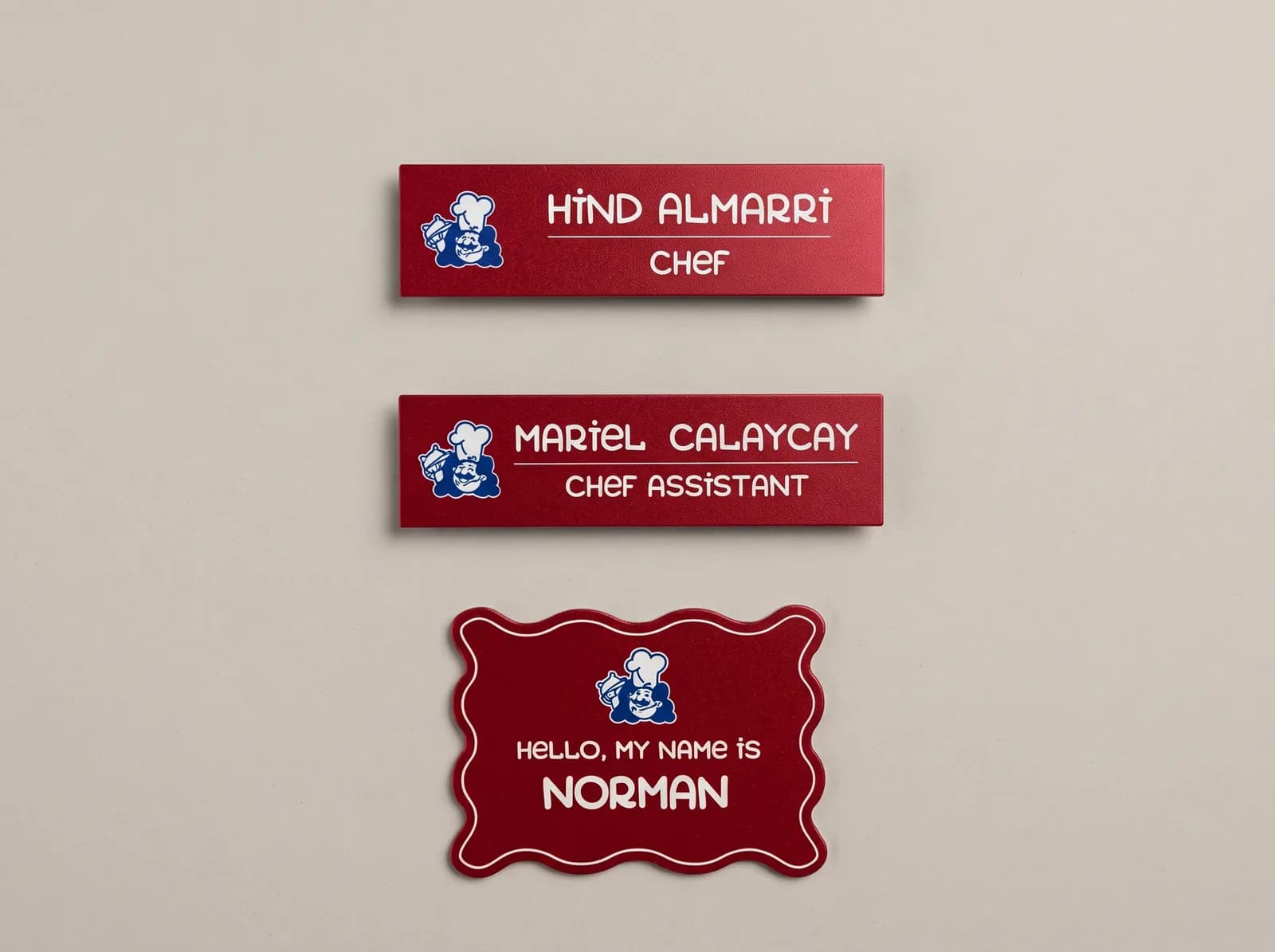 Red metal staff name badges with a restaurant logo, names and job titles