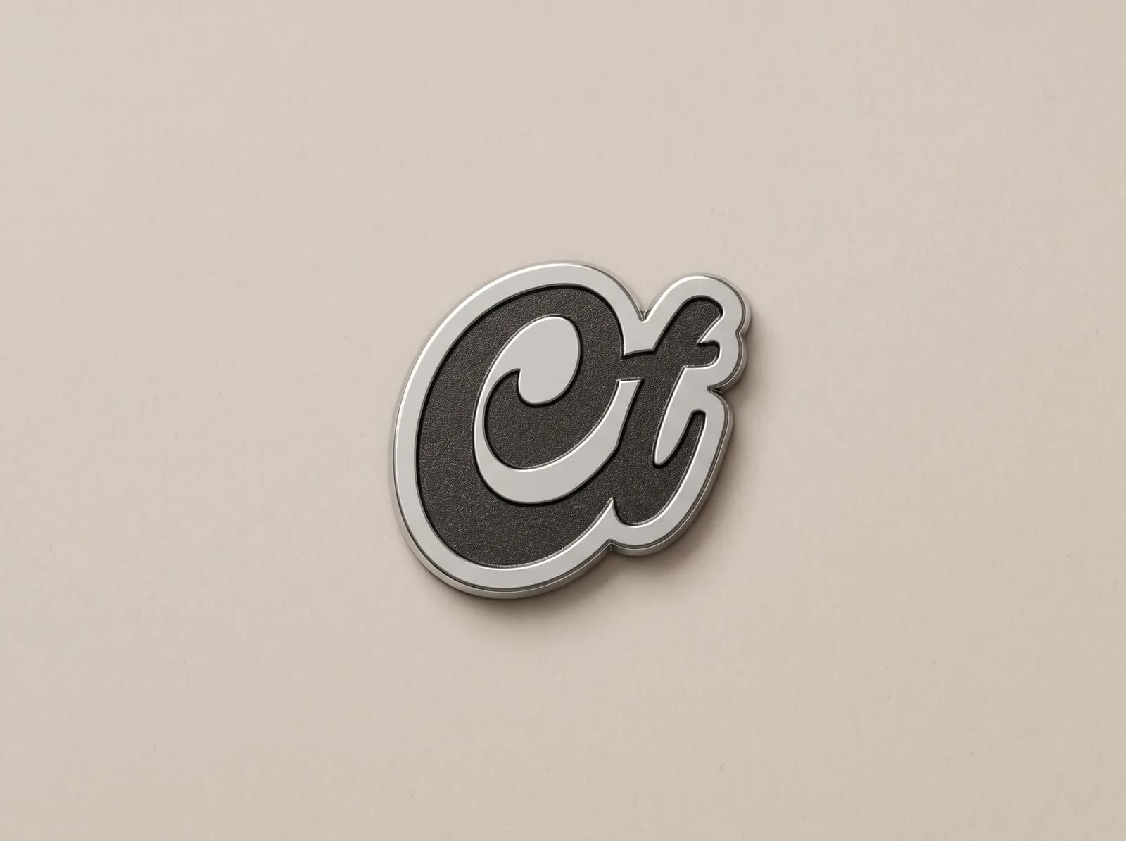 Silver metal piece cut to the shape of a script monogram