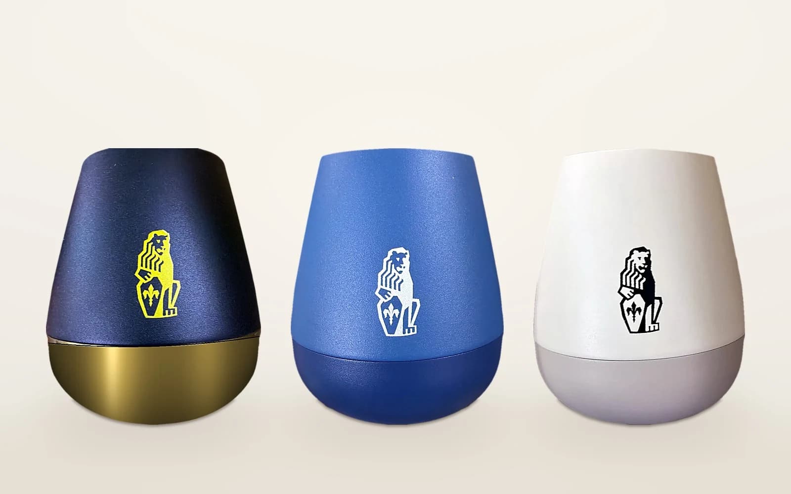 Three tumblers in black and gold, blue and white, each screen printed with the same lion logo