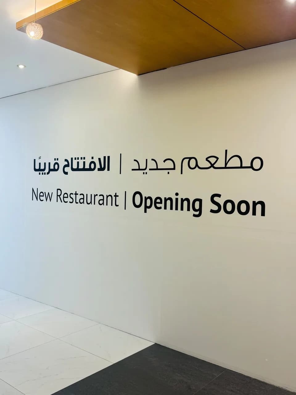 White wall with New Restaurant, Opening Soon in Arabic and English
