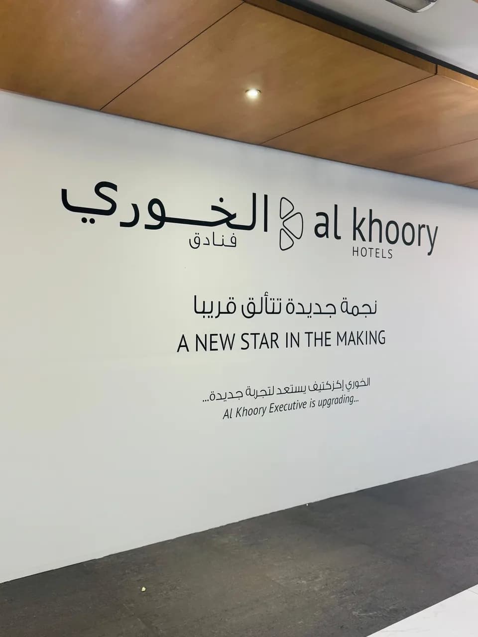 White wall with the Al Khoory Hotels logo in Arabic and English and the message A new star in the making, Al Khoory Executive is upgrading