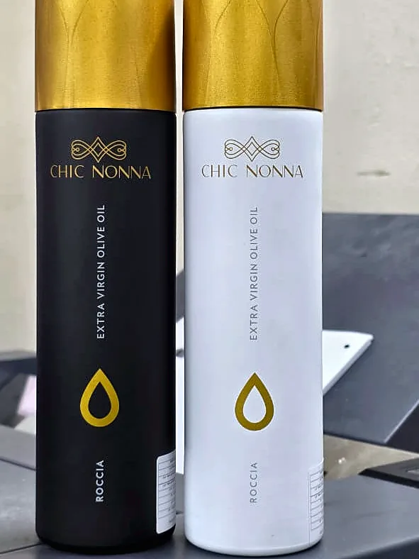 Black and white Chic Nonna extra virgin olive oil bottles with gold caps and a gold oil drop printed on each
