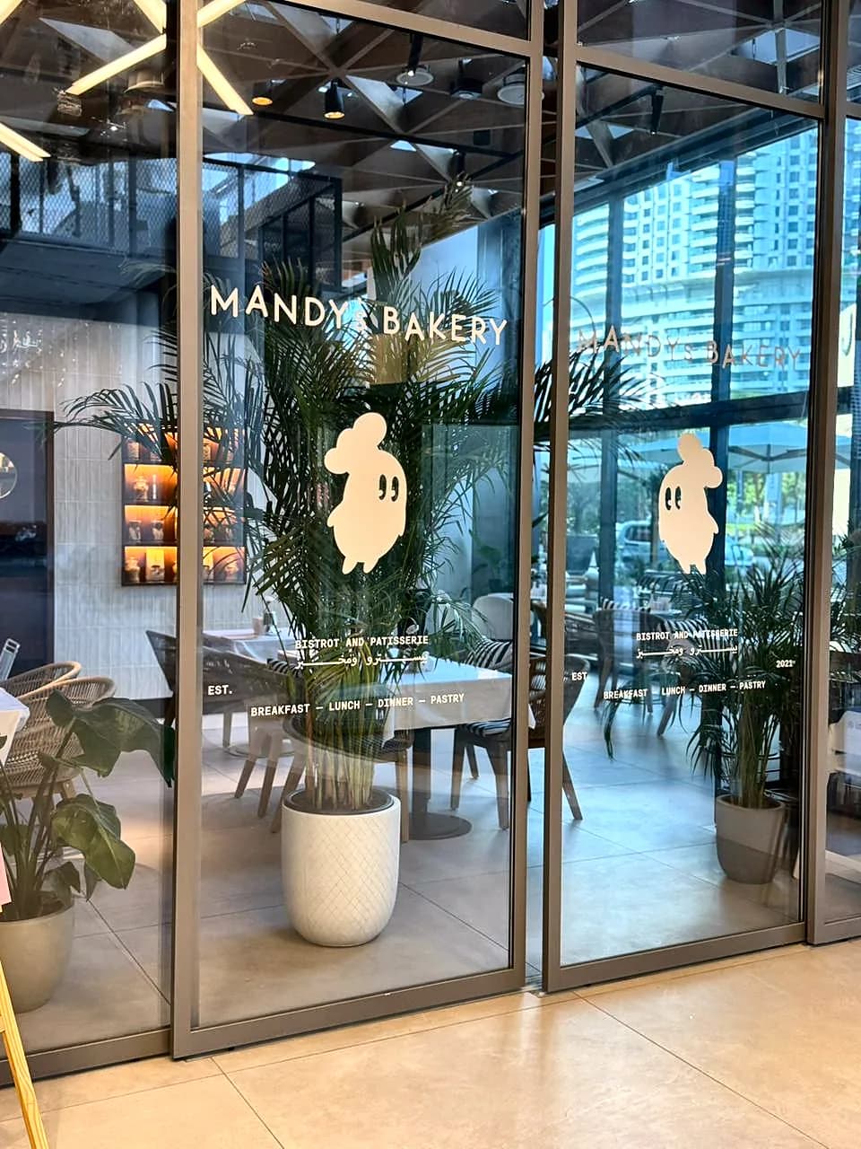 Glass front of Mandy's Bakery with the name and illustrated graphics on the doors