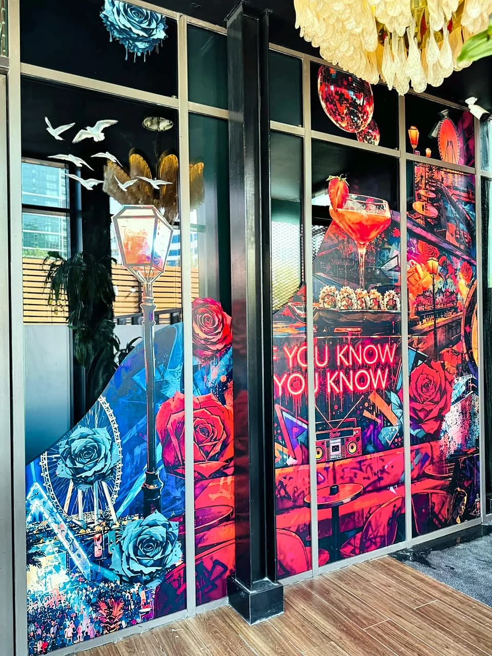 Restaurant glass front covered in colourful illustrated graphics with roses, cocktails and the words You know you know