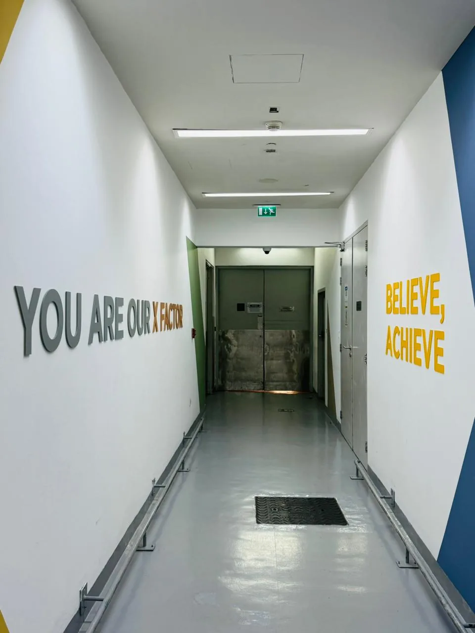 Corridor with raised grey and orange letters reading You are our X factor and yellow letters reading Believe, achieve