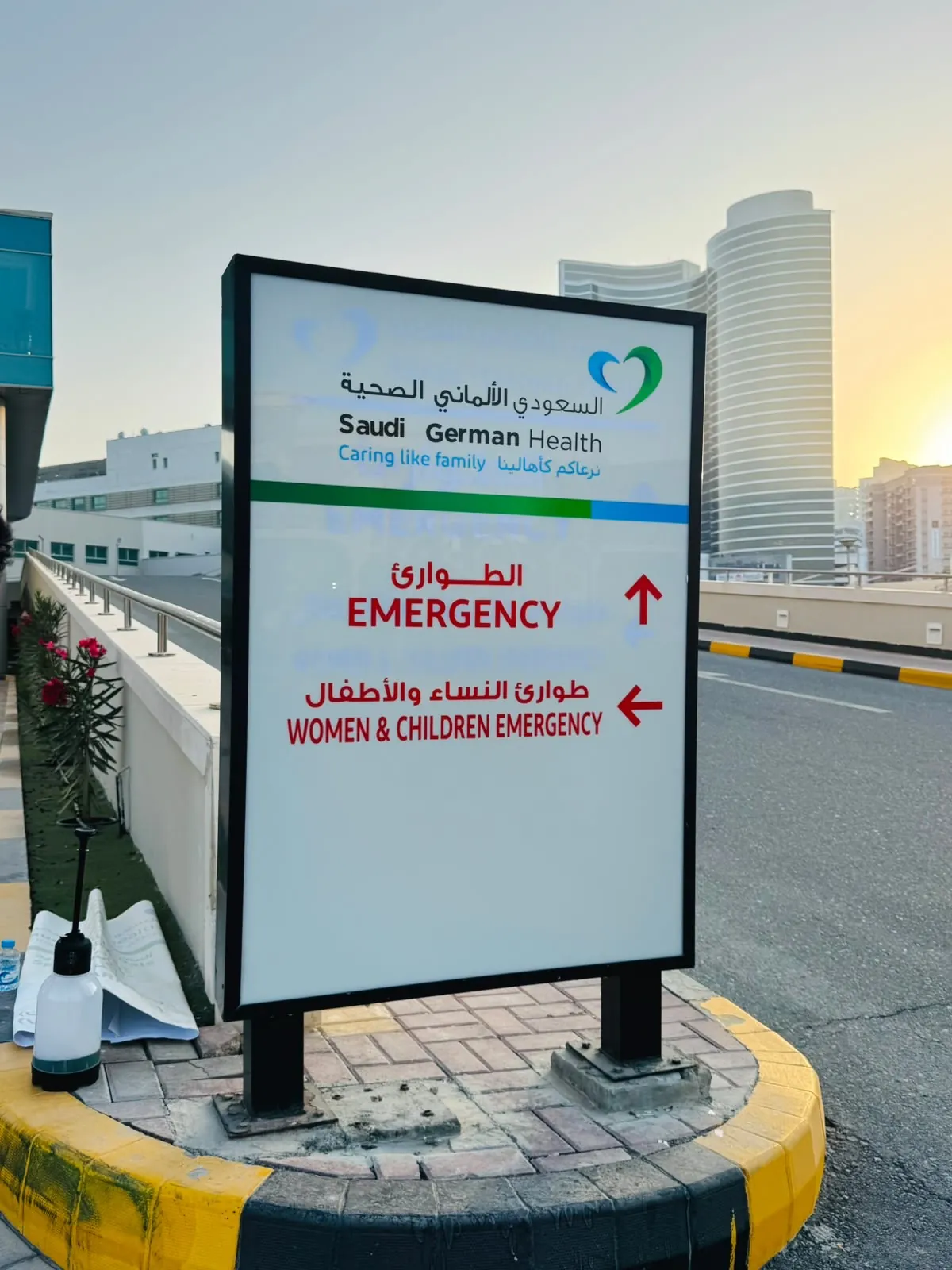 Saudi German Health directional sign pointing to Emergency and Women & Children Emergency, in Arabic and English