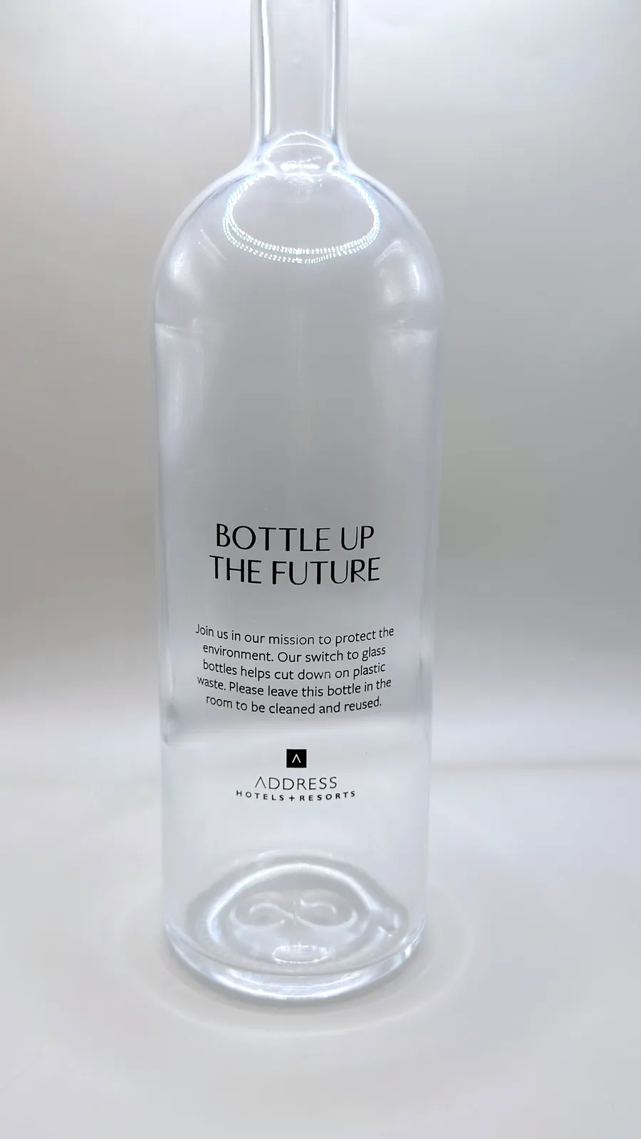 Back of an Address Hotels + Resorts glass water bottle printed with the message Bottle up the future