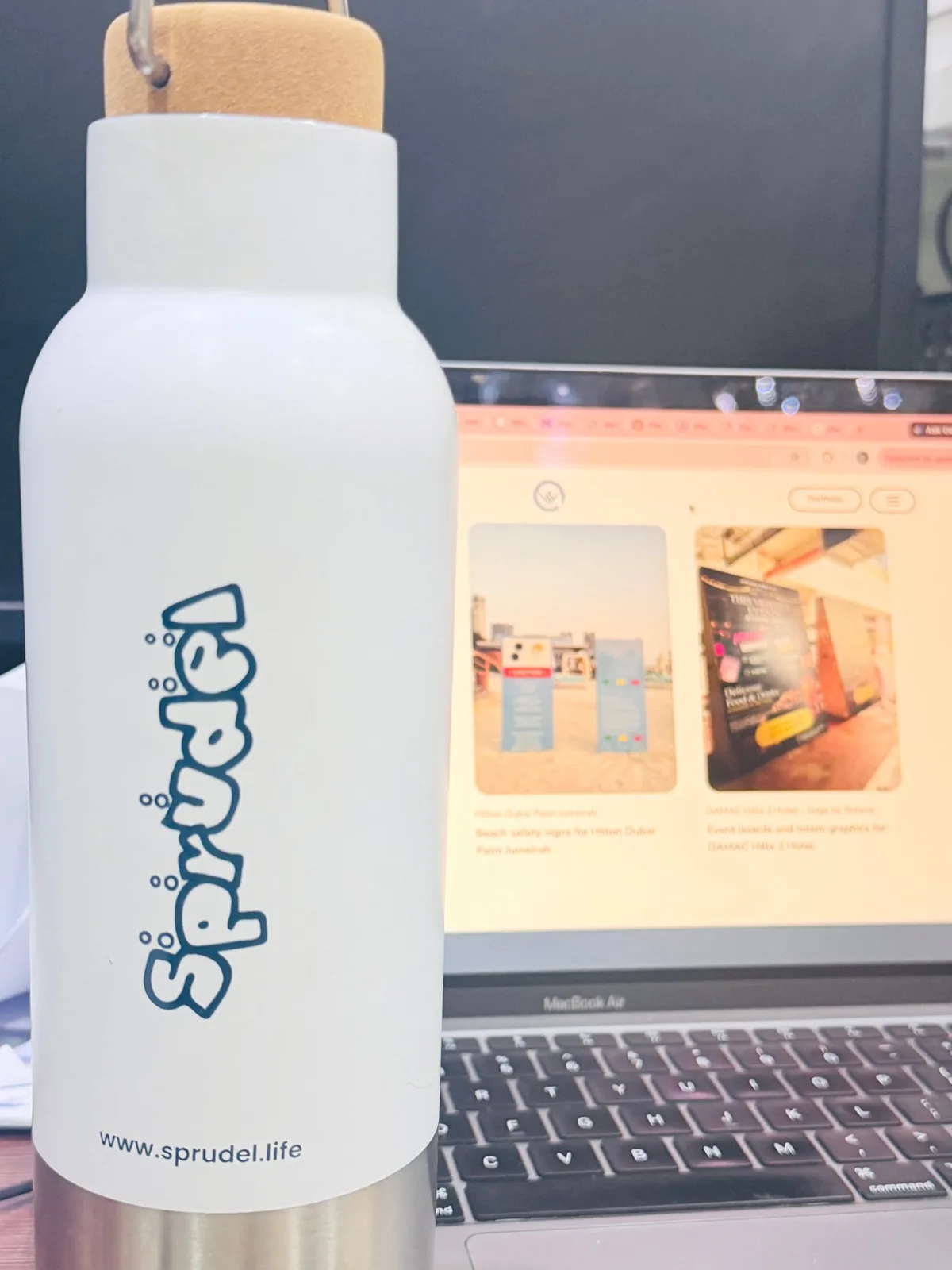 White steel water bottle with a cork lid, branded with the Sprudel logo and www.sprudel.life