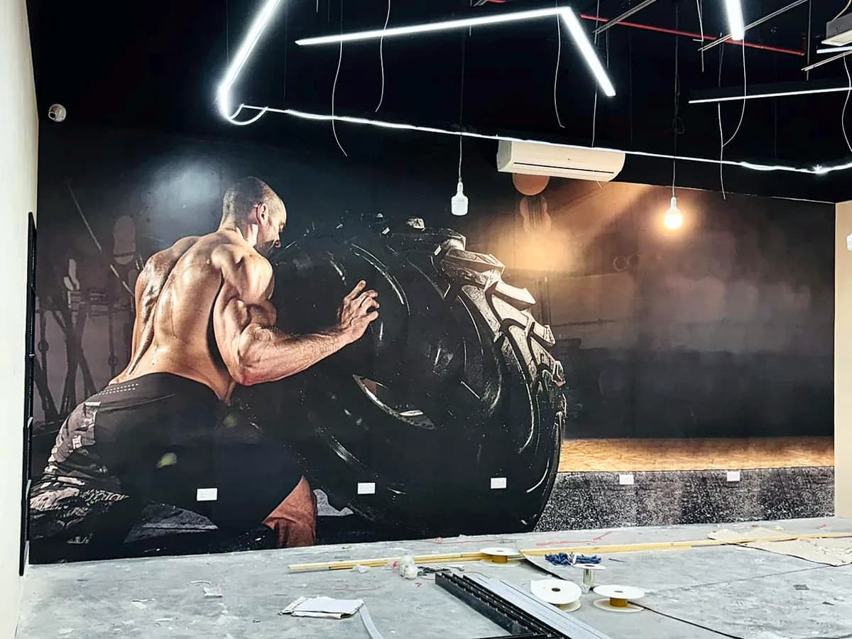 Full width gym wall mural of an athlete lifting a large tractor tyre