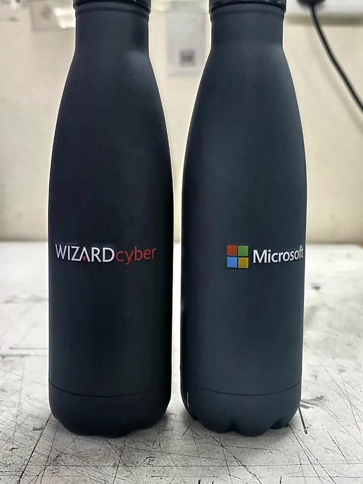 Two matte black water bottles, one branded with the WizardCyber logo and one with the Microsoft logo